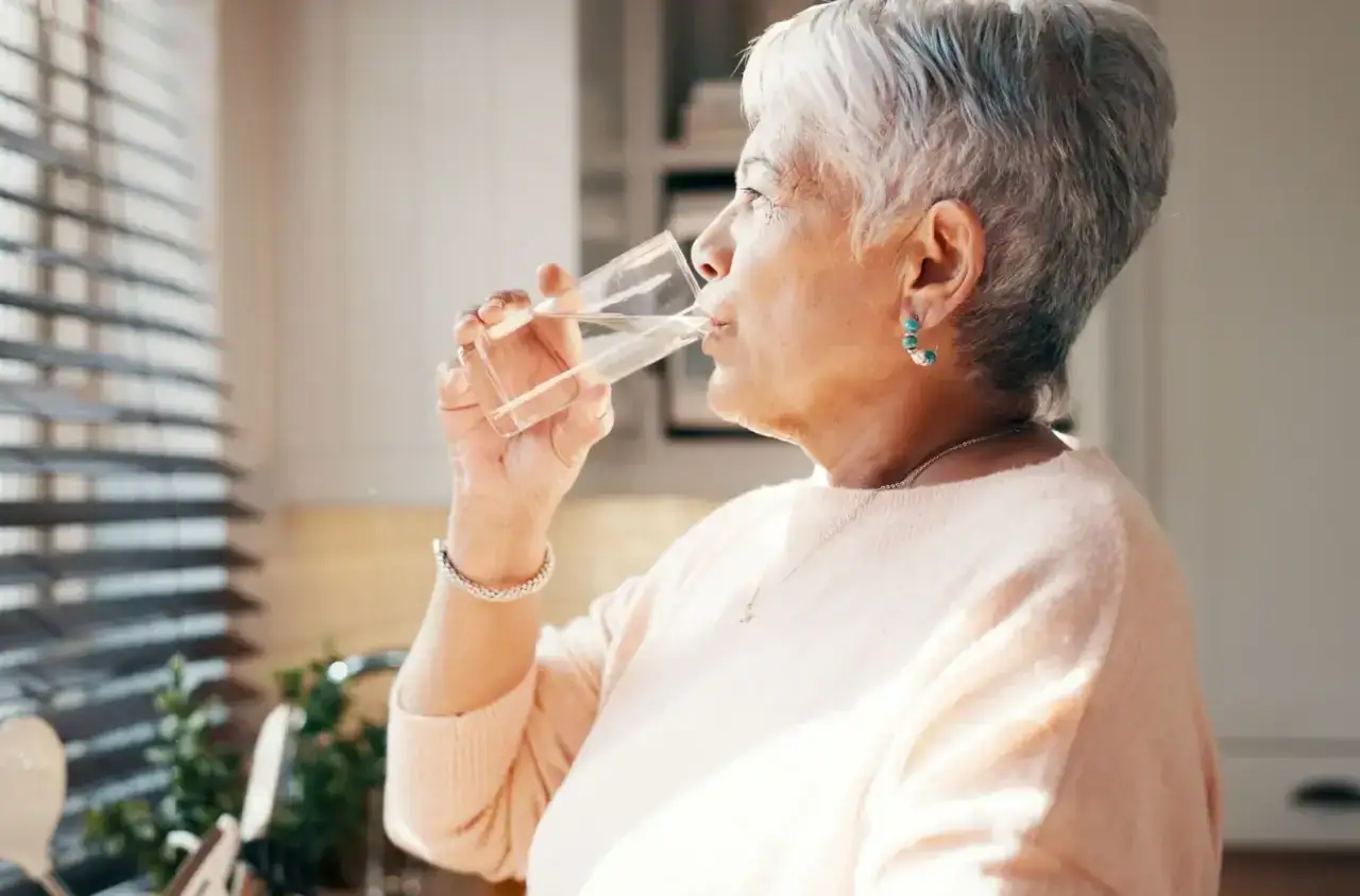 Starší žena pije vodu ze sklenice
