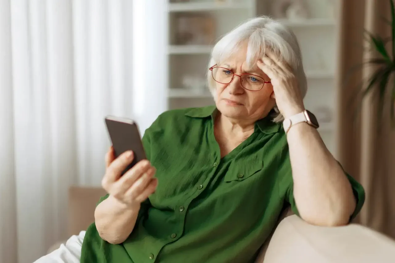 Seniorka si čte zprávy o plánovaných změnách důchodů.