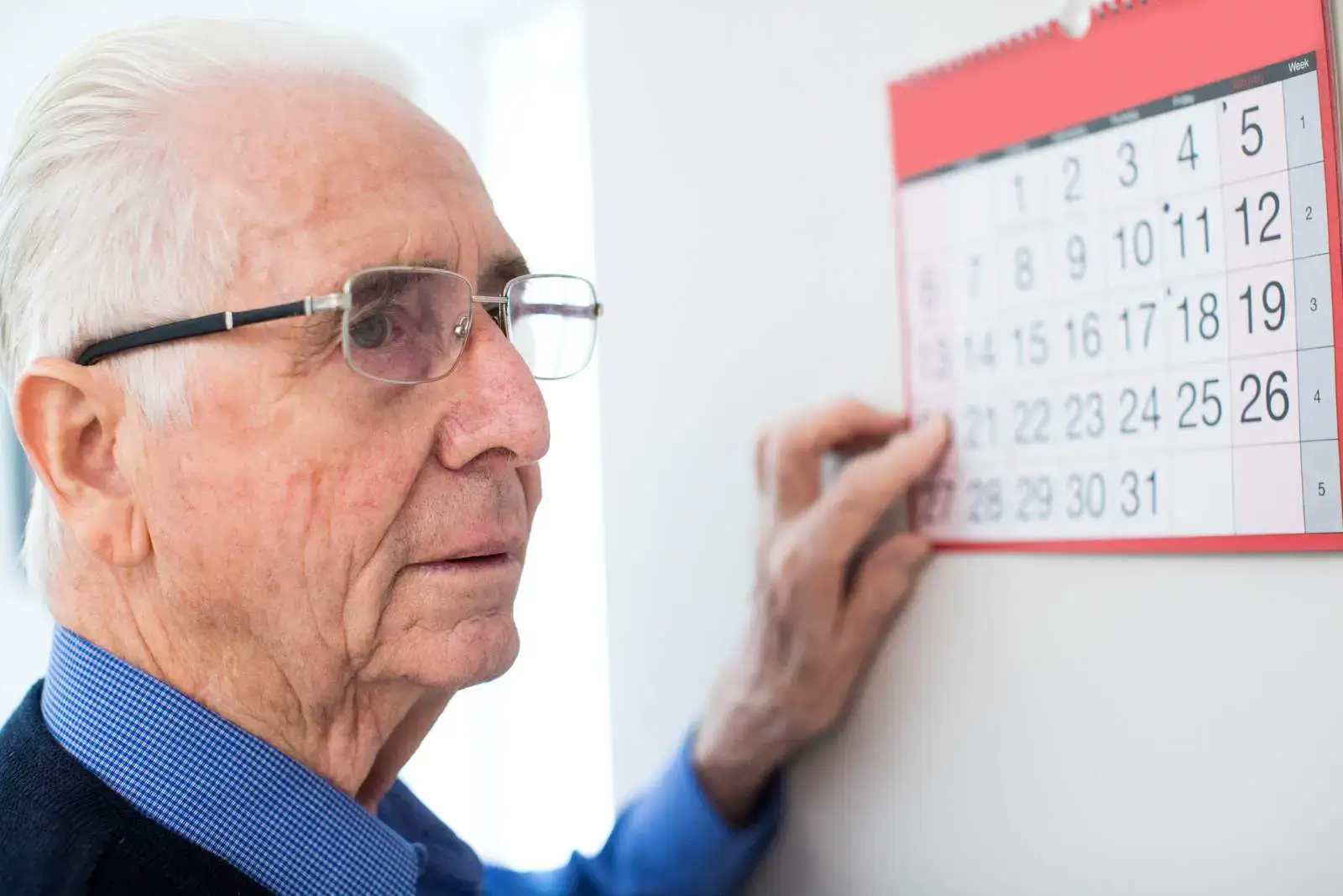 Senior se dívá na kalendář a řeší, kdy mu dorazí důchod na bankovní účet.