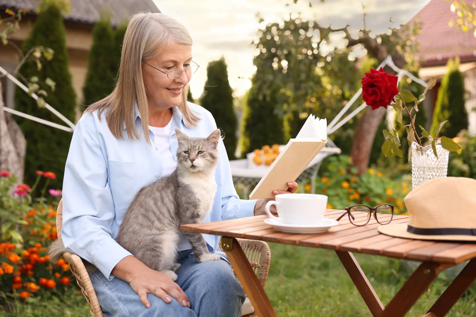 Seniorka relaxuje na zahradě při čtení knihy.