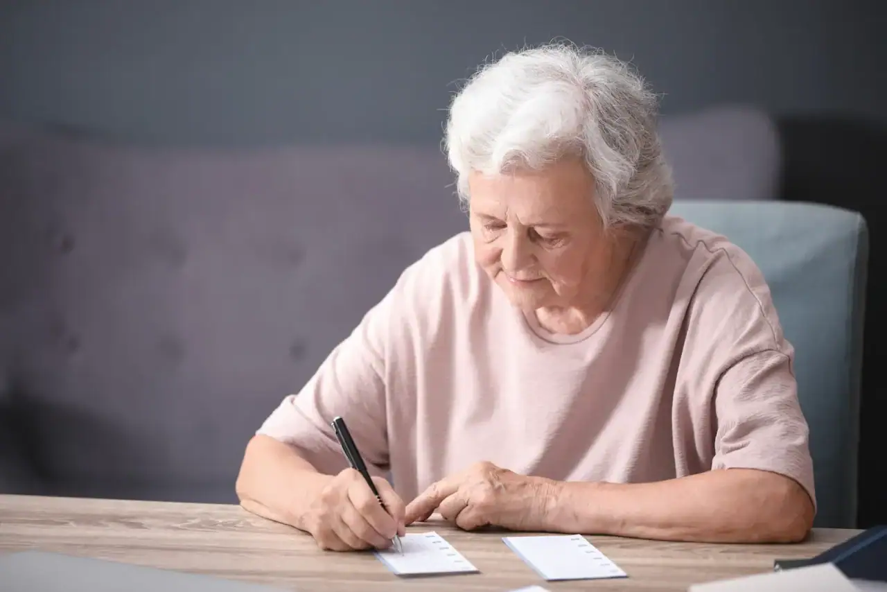 Seniorka vyplňuje papírovou sázenku.