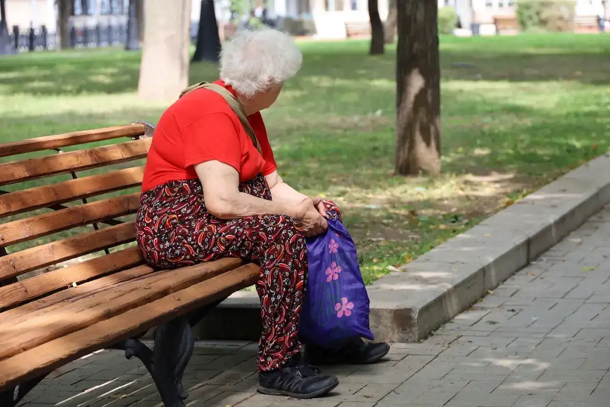 Seniorka si po cestě s nákupem sedla k odpočinku.
