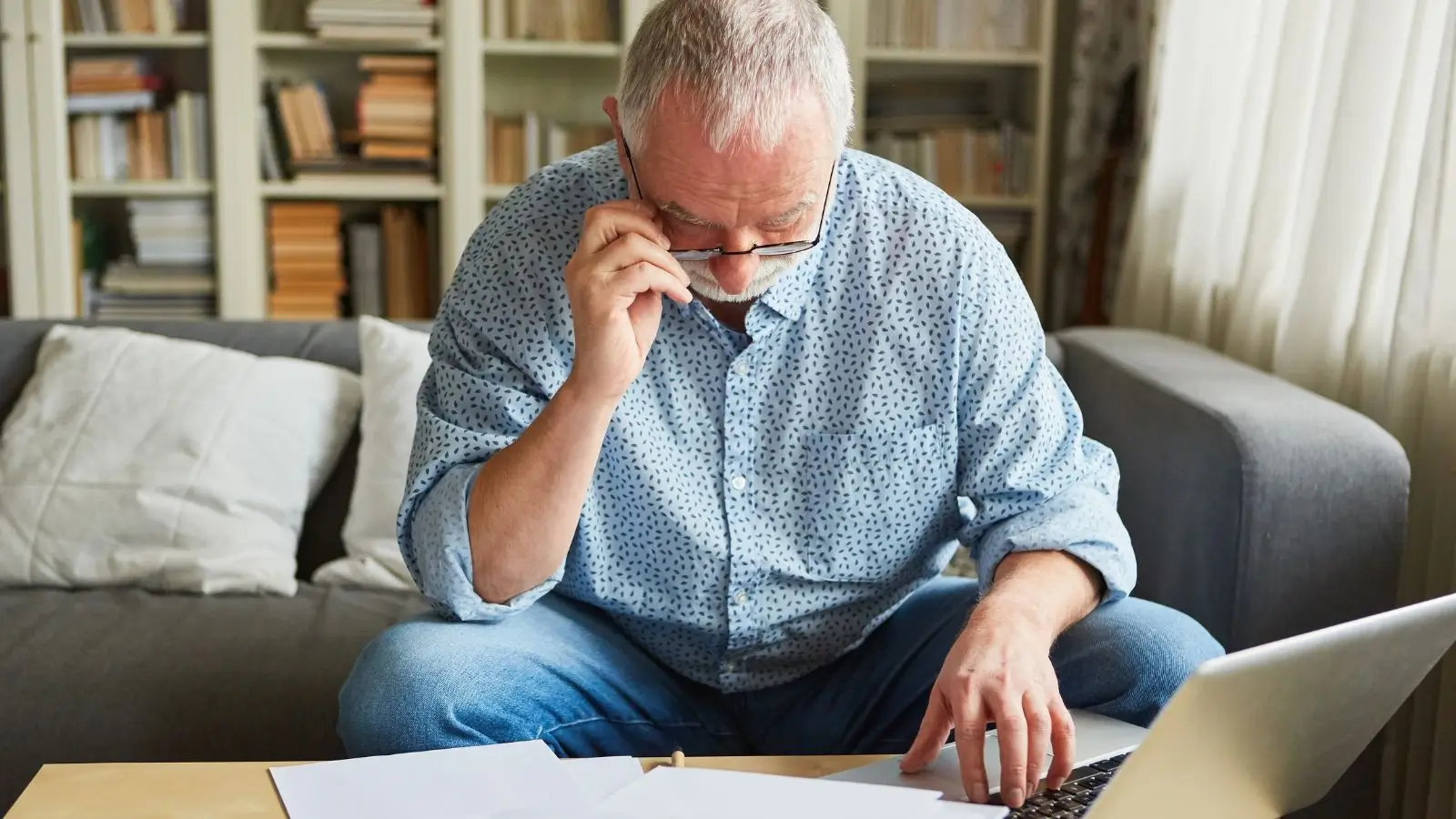 Senior vyplňuje daňové přiznání u počítače a kontroluje potřebné dokumenty. Povinnost podat přiznání může vzniknout například při podnikání, pronájmu nebo souběžných příjmech.