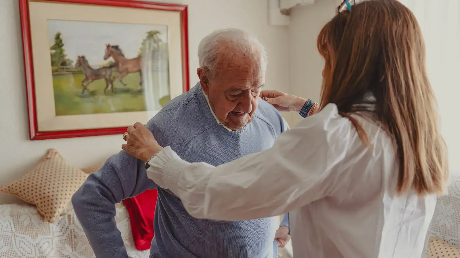 Pečovatelka pomáhá seniorovi.