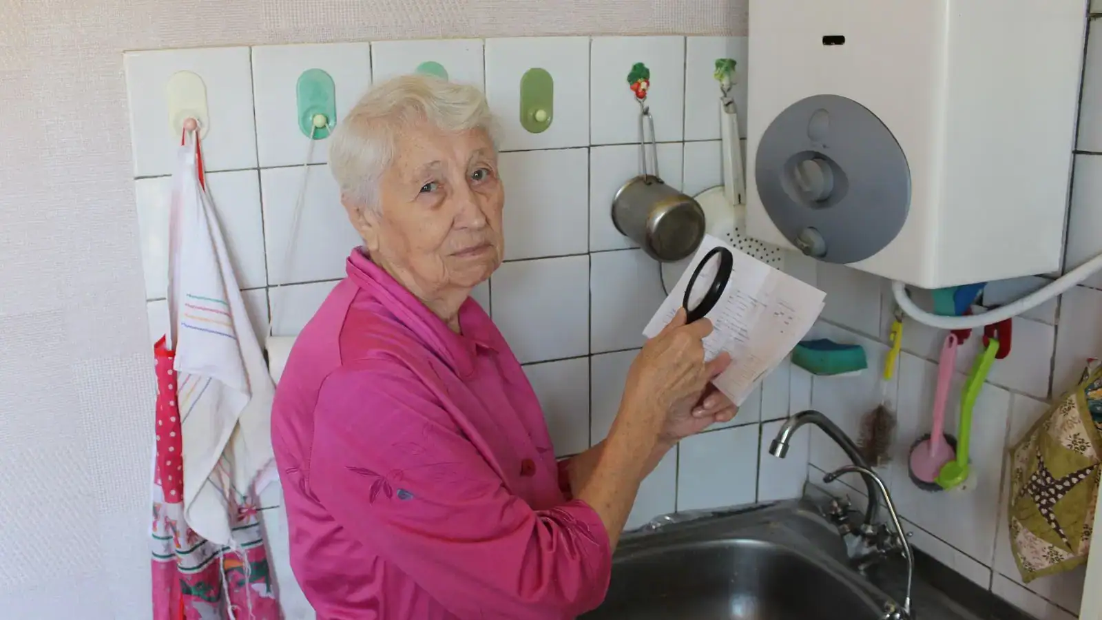 Seniorka si prohlíží vysoké účty za spotřebu.