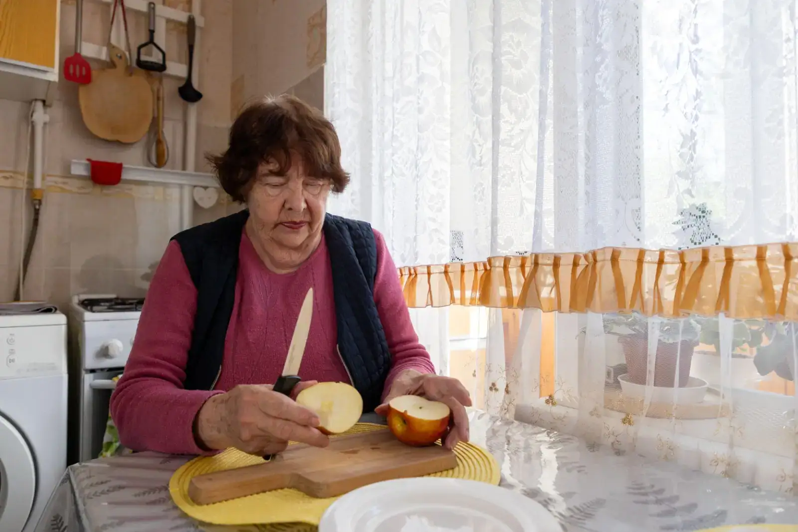 Seniorka okrajuje jablko.