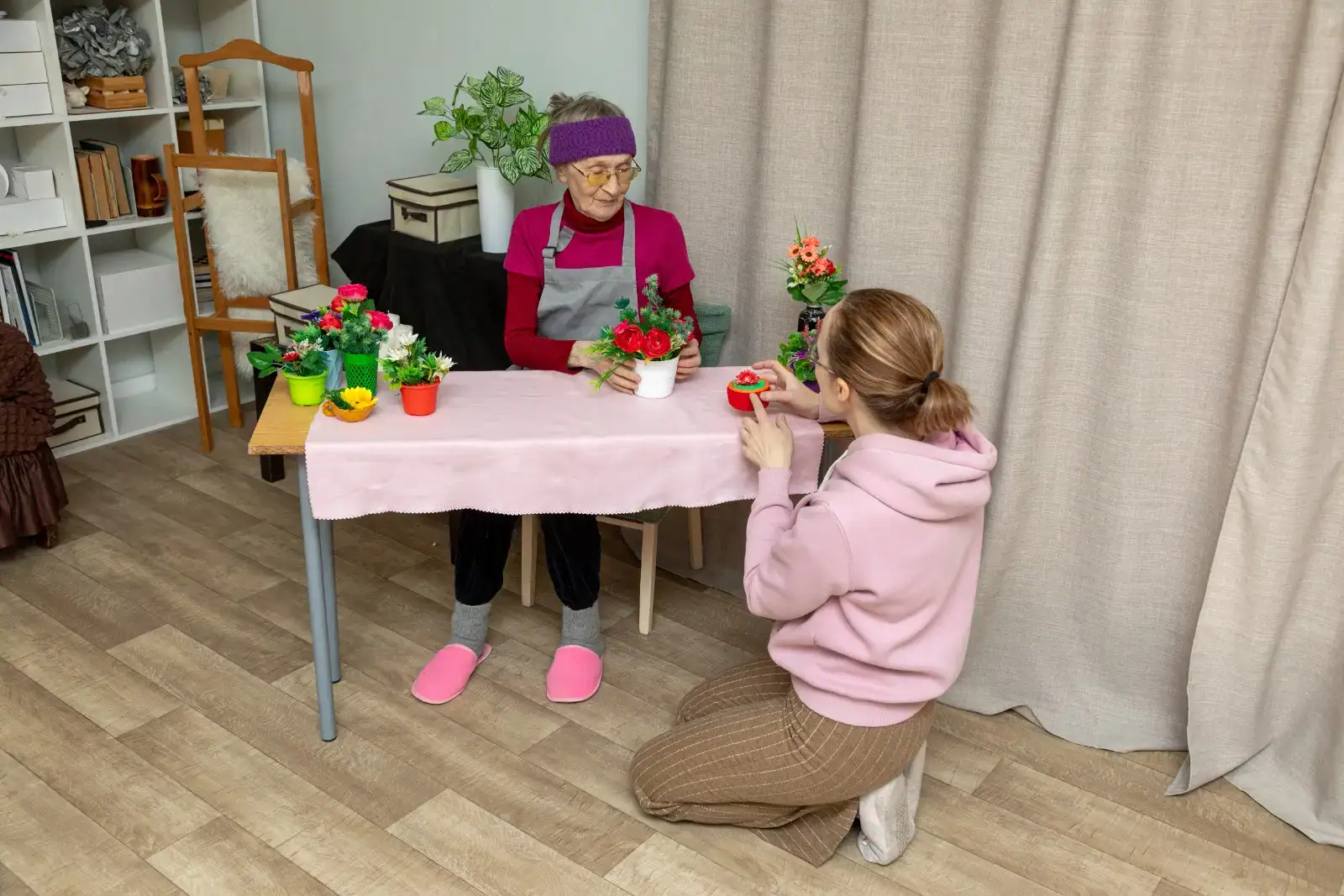 Studentka baví seniorku přesazováním rostlin.