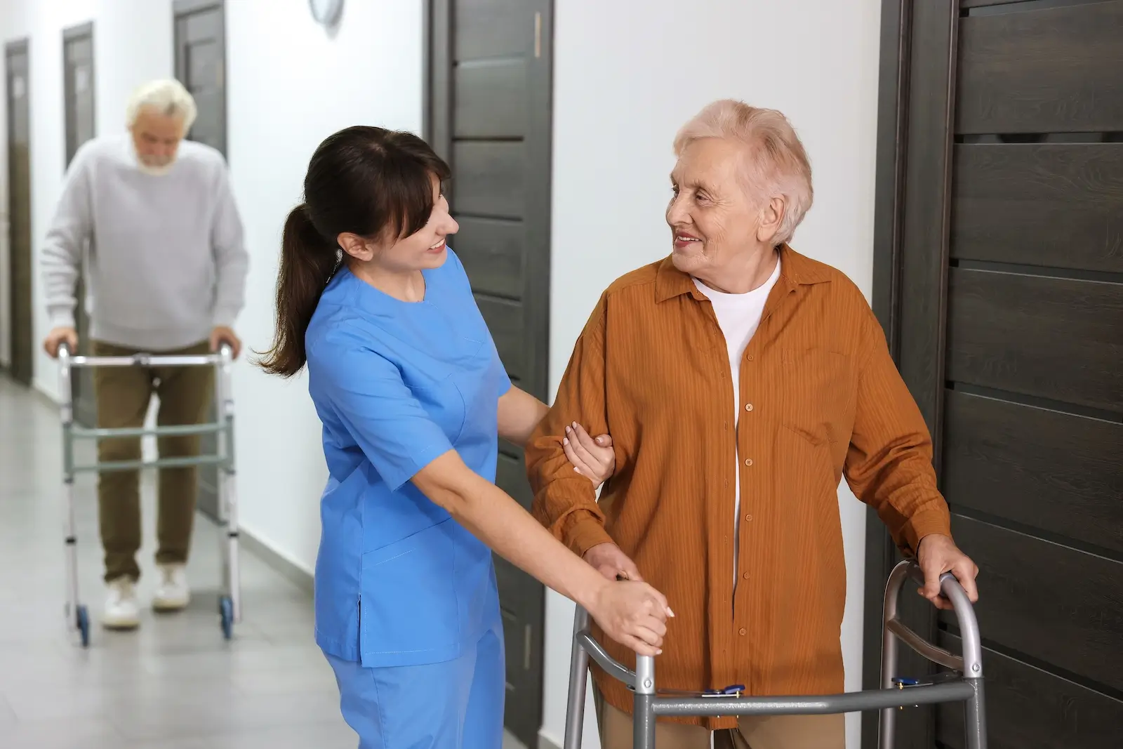 Pečovatelka pomáhá seniorce s pohybem.